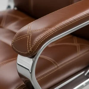A detailed shot of the hand-stitched grain leather and polished chrome armrests of a premium luxury executive office chair, showcasing its craftsmanship.