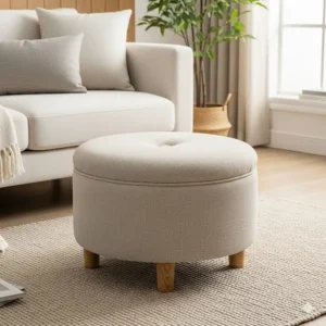 A versatile small round ottoman chair in a neutral beige color, perfect for use as a footrest or extra seating in a living room.