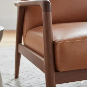 Close-up of the premium stitching on a handcrafted leather and wood accent chair.