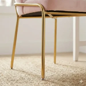Close up detail of the sturdy base of a light pink desk chair gold legs no wheels.