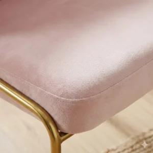 High quality velvet fabric covering the seat of a light pink desk chair gold legs no wheels.