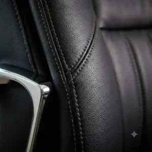 Close-up of high-quality stitching and durable material on black leather office chairs.
